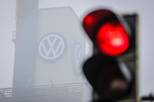 (FILES) A logo of German carmaker Volkswagen (VW) is pictured behind a red traffic light at the Volkswagen plant in Osnabruck, Germany, on November 6, 2024. German carmaker Volkwagen is in talks with defence firms to repurpose a plant in northern Germany for the production of military transport equipment, the firm's boss Oliver Blume said on March 27, 2026. (Photo by FOCKE STRANGMANN / AFP)