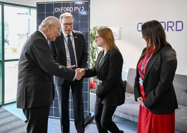 Britain's King Charles III is greeted by the executive team during a visit to Oxford Photovoltaics an enterprise developing advanced solar panels, in Kidlington, Oxfordshire, west of London on March 27, 2026. (Photo by Kate Green / POOL / AFP)