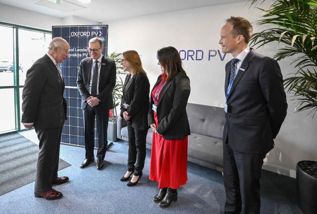 Britain's King Charles III is greeted by the executive team during a visit to Oxford Photovoltaics an enterprise developing advanced solar panels, in Kidlington, Oxfordshire, west of London on March 27, 2026. (Photo by Kate Green / POOL / AFP)
