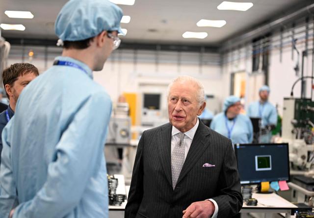 Britain's King Charles III speaks with a staff member during a visit to Oxford Photovoltaics an enterprise developing advanced solar panels, in Kidlington, Oxfordshire, west of London on March 27, 2026. (Photo by Kate Green / POOL / AFP)