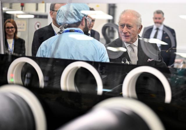 Britain's King Charles III speaks with a staff member during a visit to Oxford Photovoltaics an enterprise developing advanced solar panels, in Kidlington, Oxfordshire, west of London on March 27, 2026. (Photo by Kate Green / POOL / AFP)