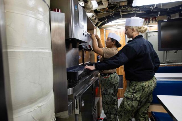 Cooks inspect the galley aboard the Virginia-class fast attack submarine USS Massachusetts (SSN 798) as it sits docked at the Conley Container Terminal before her commissioning ceremony in Boston, Massachusetts, on March 27, 2026. The US Navy will commission the Virginia-class fast attack submarine during a ceremony on March 28. (Photo by Joseph Prezioso / AFP)