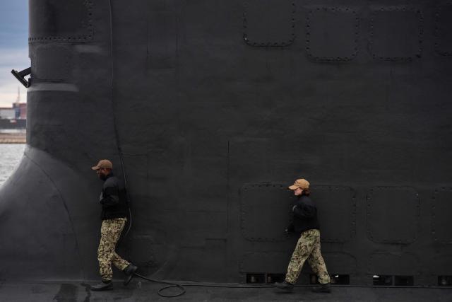 A  sailor raises the US flag on the Virginia-class fast attack submarine USS Massachusetts (SSN 798) as she sits docked at the Conley Container Terminal before her commissioning ceremony in Boston, Massachusetts, on March 27, 2026. The US Navy will commission the Virginia-class fast attack submarine during a ceremony on March 28. (Photo by Joseph Prezioso / AFP)