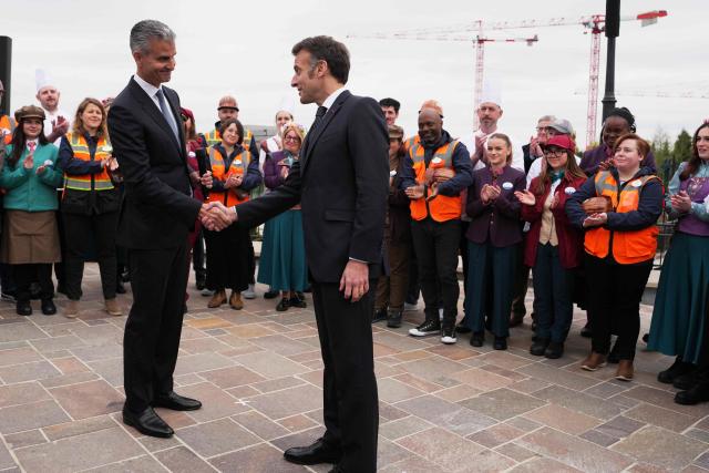 French President Emmanuel Macron (C) shakes hands with Chairman of Disney parks Josh D'Amaro (L) during the inauguration of the new Disney Adventure World theme 'World of Frozen' at Disneyland Paris in Marne-la-Vallee, east of Paris, on March 27, 2026. (Photo by Thibault Camus / POOL / AFP)