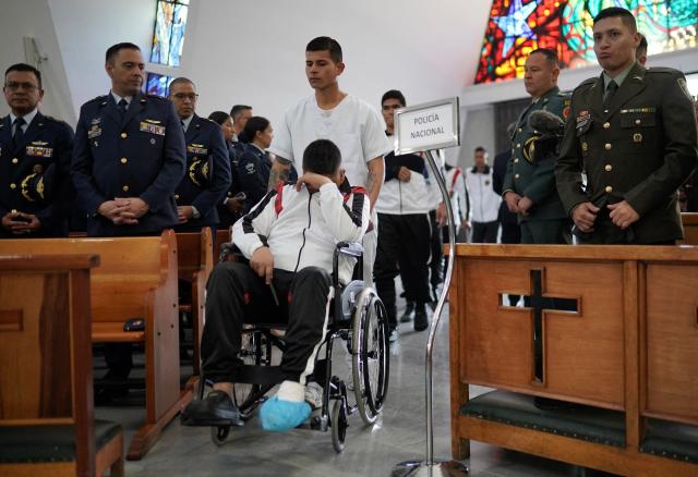 A survivor of the Air Force Hercules accident arrives in a wheelchair during a religious ceremony in Bogota on March 27, 2026. The death toll in one of Colombia's worst air accidents in recent years rose to at least 69, according to an updated tally on March 24, as the government faulted a "junk" aircraft donated by the United States. (Photo by Sergio Yate / AFP)