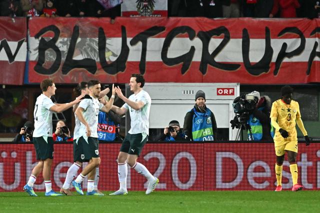 Austria's forward #11 Michael Gregoritsch (C) is celebrated by team mates after scoring the 2-0 goal as Ghana's defender #03 Caleb Yirenkyi (R) reacts during the friendly football match Austria vs Ghana in Vienna, Austria, on March 27, 2026. (Photo by Joe Klamar / AFP)
