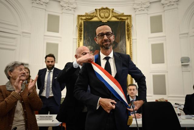 Pau's new Mayor Jerome Marbot (C) reacts as he receives the tricolour mayoral sash during his installation as Mayor of Pau at the City Hall (Hotel de Ville) of Pau, south-western France, on March 27, 2026. Marbot, a public and environmental law attorney, defeated outgoing MoDem leader Francois Bayrou by 344 votes in the second round of municipal elections on March 22. (Photo by Philippe LOPEZ / AFP)