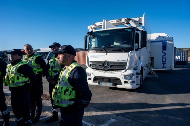 French customs' officers stand next to the low-intensity mobile scanner during the visit of France's junior Minister for Public Accounts at the Grand Port Maritime of Marseille, southeastern France on March 27, 2026.  (Photo by Elodie CLEMENT / AFP)