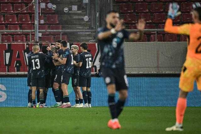 Paraguay's midfielder #08 Diego Gomez (hidden) celebrates with teammates scoring his team's first goal during a friendly football match between Greece and Paraguay at the Georgios Karaiskaki Stadium in Athens on March 27, 2026.  (Photo by Aris MESSINIS / AFP)