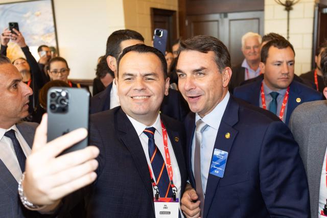 Brazilian senator and son of former president Jair Bolsonaro, Flavio Bolsonaro takes pictures with an attendee during the Conservative Political Action Conference (CPAC) in Grapevine, Texas, on March 27, 2026. American conservatives converge on Texas this week for what organizers bill as their largest and most influential gathering, with the Iran war and fears of a punishing midterm election cycle heightening the stakes. (Photo by Leandro Lozada / AFP)