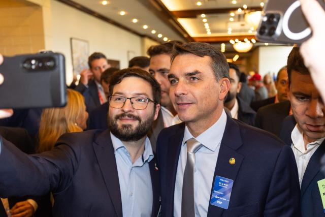 Brazilian senator and son of former president Jair Bolsonaro, Flavio Bolsonaro takes pictures with an attendee during the Conservative Political Action Conference (CPAC) in Grapevine, Texas, on March 27, 2026. American conservatives converge on Texas this week for what organizers bill as their largest and most influential gathering, with the Iran war and fears of a punishing midterm election cycle heightening the stakes. (Photo by Leandro Lozada / AFP)