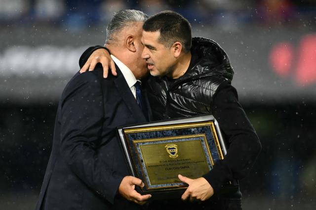 Boca Juniors' president Juan Roman Riquelme (R) presents Argentine Football Association (AFA) president Claudio Tapia with a recognition plaque ahead of a friendly football match between Argentina and Mauritania at La Bombonera stadium in Buenos Aires on March 27, 2026. (Photo by Luis ROBAYO / AFP)