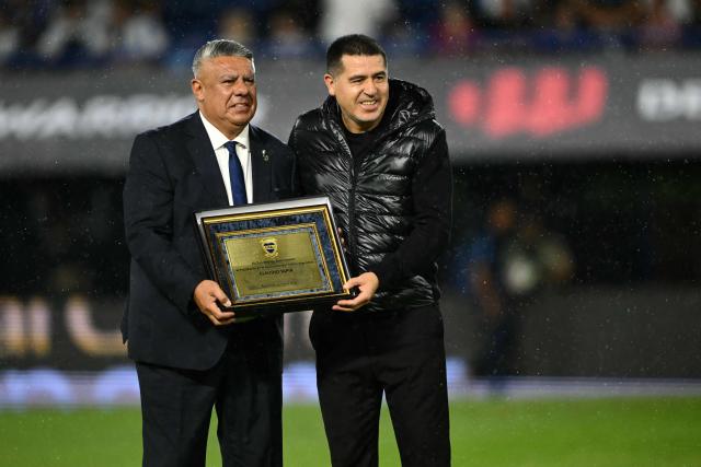Boca Juniors' president Juan Roman Riquelme (R) presents Argentine Football Association (AFA) president Claudio Tapia with a recognition plaque ahead of a friendly football match between Argentina and Mauritania at La Bombonera stadium in Buenos Aires on March 27, 2026. (Photo by Luis ROBAYO / AFP)