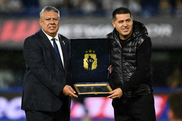 Boca Juniors' president Juan Roman Riquelme (R) presents Argentine Football Association (AFA) president Claudio Tapia with a recognition plaque ahead of a friendly football match between Argentina and Mauritania at La Bombonera stadium in Buenos Aires on March 27, 2026. (Photo by Luis ROBAYO / AFP)