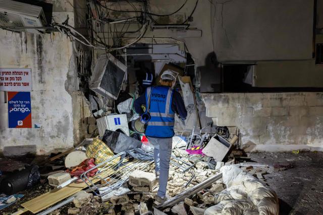 Workers inspect a building damaged by a strike in Tel Aviv, on March 28, 2026. On the evening of March 27, the Israeli army reported missiles fired by Iran at Israel. (Photo by Ilia YEFIMOVICH / AFP) / 