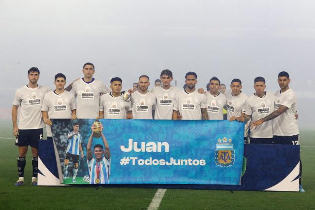 Argentina players pose with a banner and wearing T-shirts in support of their teammates Juan Foyth and Joaquin Panichelli, who will miss the World Cup, ahead of a friendly football match between Argentina and Mauritania at La Bombonera stadium in Buenos Aires on March 27, 2026. (Photo by ALEJANDRO PAGNI / AFP)