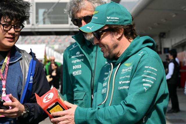 Aston Martin's Spanish driver Fernando Alonso receives a gift from a fan as he arrives for the third practice session ahead of the Formula One Japanese Grand Prix at the Suzuka circuit in Suzuka, Mie prefecture on March 28, 2026. (Photo by Toshifumi KITAMURA / AFP)