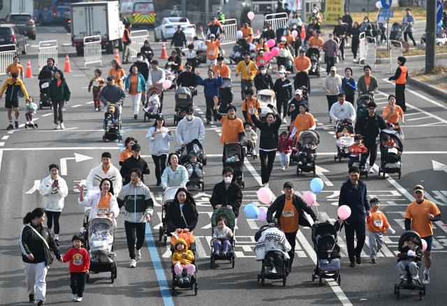 Participants run with strollers during the 2026 Seoul Stroller Run, a family-focused 8km event hosted by the Seoul Metropolitan Government, in central Seoul on March 28, 2026. (Photo by Jung Yeon-je / AFP)