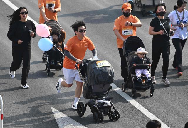 Participants run with strollers during the 2026 Seoul Stroller Run, a family-focused 8km event hosted by the Seoul Metropolitan Government, in central Seoul on March 28, 2026. (Photo by Jung Yeon-je / AFP)