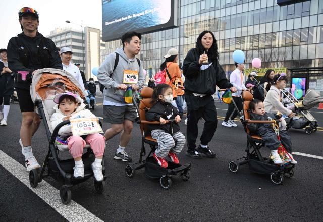 Participants run with strollers during the 2026 Seoul Stroller Run, a family-focused 8km event hosted by the Seoul Metropolitan Government, in central Seoul on March 28, 2026. (Photo by Jung Yeon-je / AFP)