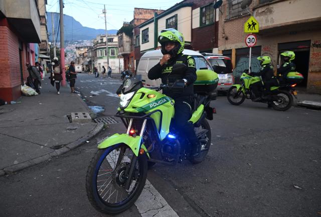Colombian police officers patrol the San Bernardo neighborhood, a critical, high-risk zone known for micro-trafficking, insecurity, and social conflict in downtown Bogota on March 26, 2026. Colombian police use an artificial intelligence tool to predict crime hotspots in real time and create security plans based on large amounts of geographic data. The software, called "IAPol," shows on a map the areas where different risk factors come together, like crime statistics, emergency calls, and police presence, allowing for quicker planning in a country with high crime rates. (Photo by Raul ARBOLEDA / AFP)