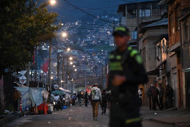 A Colombian police officer patrols the San Bernardo neighborhood, a critical, high-risk zone known for micro-trafficking, insecurity, and social conflict in downtown Bogota on March 26, 2026. Colombian police use an artificial intelligence tool to predict crime hotspots in real time and create security plans based on large amounts of geographic data. The software, called "IAPol," shows on a map the areas where different risk factors come together, like crime statistics, emergency calls, and police presence, allowing for quicker planning in a country with high crime rates. (Photo by Raul ARBOLEDA / AFP)