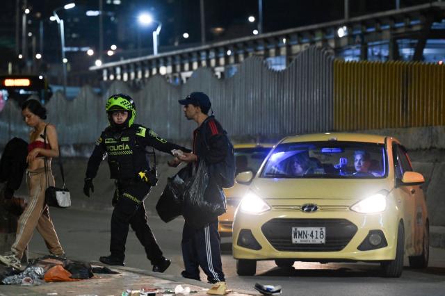 A Colombian police officer patrols the San Bernardo neighborhood, a critical, high-risk zone known for micro-trafficking, insecurity, and social conflict in downtown Bogota on March 26, 2026. Colombian police use an artificial intelligence tool to predict crime hotspots in real time and create security plans based on large amounts of geographic data. The software, called "IAPol," shows on a map the areas where different risk factors come together, like crime statistics, emergency calls, and police presence, allowing for quicker planning in a country with high crime rates. (Photo by Raul ARBOLEDA / AFP)