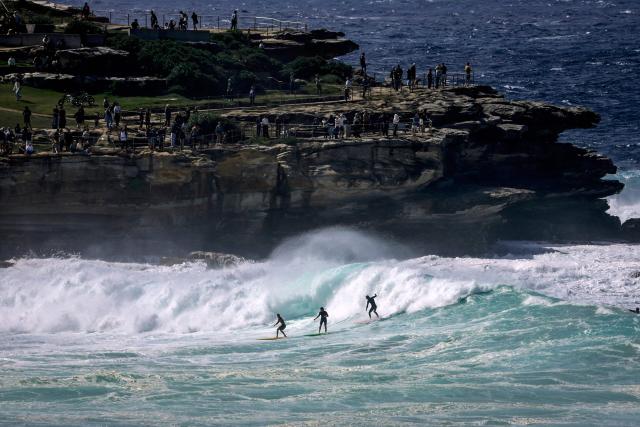 Crowds watch surfers catching large waves breaking at Bondi Beach in Sydney on March 28, 2026 as large swells and high winds create hazardous surf conditions along the south-east coast of Australia. (Photo by DAVID GRAY / AFP)