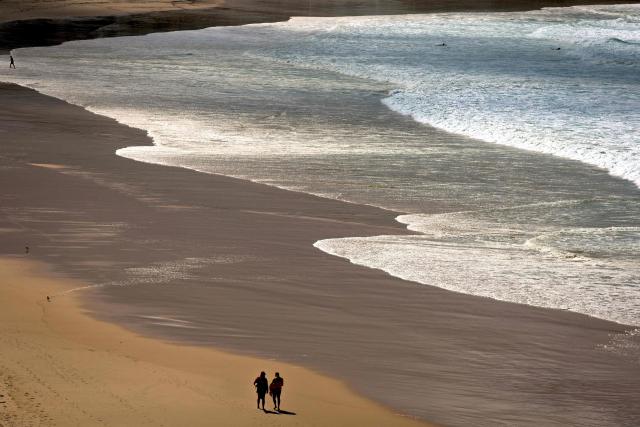 Surf lifesavers walk along an almost empty Bondi Beach in Sydney on March 28, 2026 as large swells and high winds create hazardous surf conditions along the south-east coast of Australia. (Photo by DAVID GRAY / AFP)