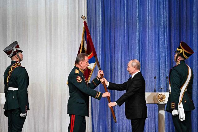 In this pool photograph distributed by the Russian state agency Sputnik, Russian President Vladimir Putin hand over a flag to the Director of the Federal Service of National Guard Troops - Commander-in-Chief of the National Guard Troops of the Russian Federation (Rosgvardia) Viktor Zolotov (L) during a gala evening in the State Kremlin Palace in Moscow dedicated to the 10th anniversary of the Rosgvardia, on March 27, 2026. (Photo by Sergei BOBYLYOV / POOL / AFP)