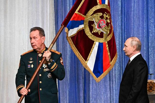 In this pool photograph distributed by the Russian state agency Sputnik, Russian President Vladimir Putin hands over a flag to the Director of the Federal Service of National Guard Troops - Commander-in-Chief of the National Guard Troops of the Russian Federation (Rosgvardia) Viktor Zolotov (L) during a gala evening in the State Kremlin Palace in Moscow dedicated to the 10th anniversary of the Rosgvardia, on March 27, 2026. (Photo by Sergei BOBYLYOV / POOL / AFP)