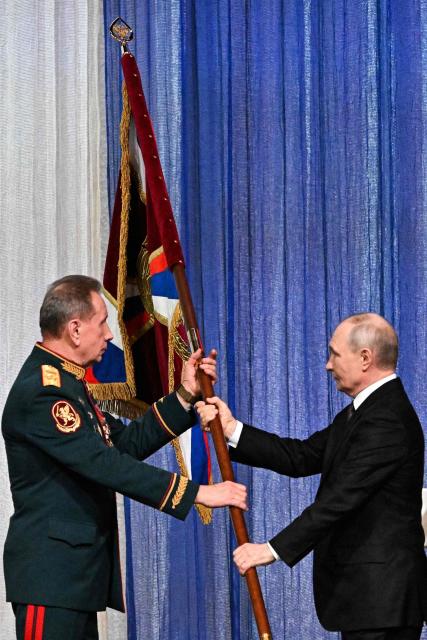 In this pool photograph distributed by the Russian state agency Sputnik, Russian President Vladimir Putin hands over a flag to the Director of the Federal Service of National Guard Troops - Commander-in-Chief of the National Guard Troops of the Russian Federation (Rosgvardia) Viktor Zolotov (L) during a gala evening in the State Kremlin Palace in Moscow dedicated to the 10th anniversary of the Rosgvardia, on March 27, 2026. (Photo by Sergei BOBYLYOV / POOL / AFP)