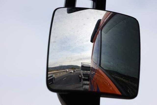 French truck drivers, seen in a rearview mirror, block the A7 motorway, south of Lyon, to protest against rising fuel prices, in Chasse-sur-Rhône, central eastern France, on March 28, 2026. (Photo by Alex MARTIN / AFP)