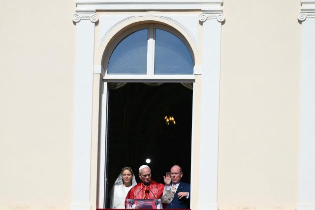 Pope Leo XIV  gives a speech from the balcony next to Prince's Albert II of Monaco (R) and Princess Charlene of Monaco at the Prince's Palace of Monaco in Monte Carlo, Monaco, on March 28, 2026. Pope Leo XIV heads to the Mediterranean principality of Monaco on the French Riviera that is the pontiff's surprise pick for the first western European trip of his papacy. The US-born pope, a former missionary critical of the wealthy elite, will helicopter in for a day in the world's second-smallest state, best known for its casinos, luxury yachts and Michelin-starred dining. (Photo by Marco BERTORELLO / AFP)