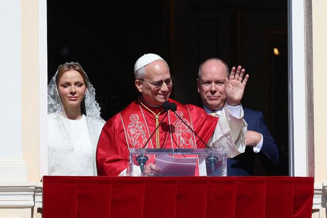 Pope Leo XIV waves as he gives a speech from the balcony next to Prince's Albert II of Monaco (R) and Princess Charlene of Monaco at the Prince's Palace of Monaco in Monte Carlo, Monaco, on March 28, 2026. Pope Leo XIV heads to the Mediterranean principality of Monaco on the French Riviera that is the pontiff's surprise pick for the first western European trip of his papacy. The US-born pope, a former missionary critical of the wealthy elite, will helicopter in for a day in the world's second-smallest state, best known for its casinos, luxury yachts and Michelin-starred dining. (Photo by Valery HACHE / AFP)