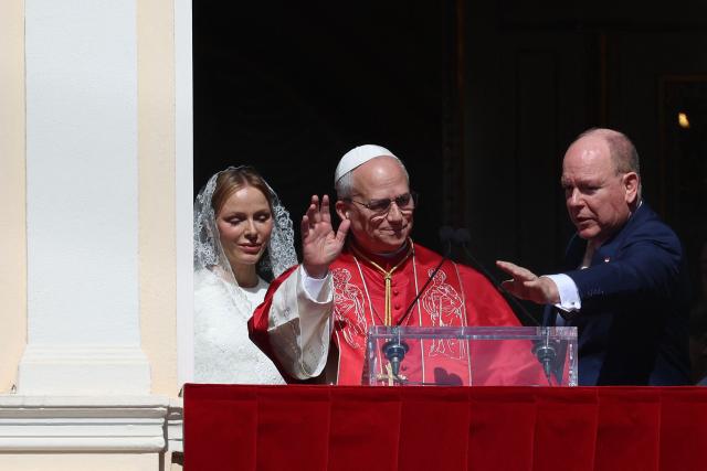 Pope Leo XIV gives a speech from the balcony next to Prince's Albert II of Monaco (R) and Princess Charlene of Monaco at the Prince's Palace of Monaco in Monte Carlo, Monaco, on March 28, 2026. Pope Leo XIV heads to the Mediterranean principality of Monaco on the French Riviera that is the pontiff's surprise pick for the first western European trip of his papacy. The US-born pope, a former missionary critical of the wealthy elite, will helicopter in for a day in the world's second-smallest state, best known for its casinos, luxury yachts and Michelin-starred dining. (Photo by Valery HACHE / AFP)