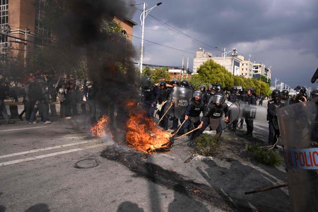 Police douse a burning tire while Nepali former prime minister KP Sharma Oli's supporters protest against his arrest in Kathmandu on March 28, 2026. Nepal's former prime minister KP Sharma Oli and ex-home minister Ramesh Lekhak were arrested March 28 over their alleged involvement in a deadly crackdown on protestors in September, police said. (Photo by PRAKASH MATHEMA / AFP)