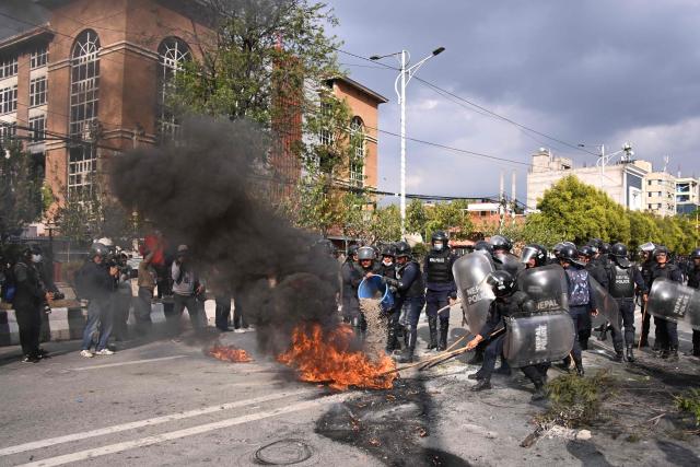 Police douse a burning tire while Nepali former prime minister KP Sharma Oli's supporters protest against his arrest in Kathmandu on March 28, 2026. Nepal's former prime minister KP Sharma Oli and ex-home minister Ramesh Lekhak were arrested March 28 over their alleged involvement in a deadly crackdown on protestors in September, police said. (Photo by PRAKASH MATHEMA / AFP)