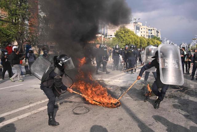 Police douse a burning tire while Nepali former prime minister KP Sharma Oli's supporters protest against his arrest in Kathmandu on March 28, 2026. Nepal's former prime minister KP Sharma Oli and ex-home minister Ramesh Lekhak were arrested March 28 over their alleged involvement in a deadly crackdown on protestors in September, police said. (Photo by PRAKASH MATHEMA / AFP)