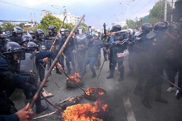 Police douse burning tires while Nepali former prime minister KP Sharma Oli's supporters protest against his arrest in Kathmandu on March 28, 2026. Nepal's former prime minister KP Sharma Oli and ex-home minister Ramesh Lekhak were arrested March 28 over their alleged involvement in a deadly crackdown on protestors in September, police said. (Photo by PRAKASH MATHEMA / AFP)