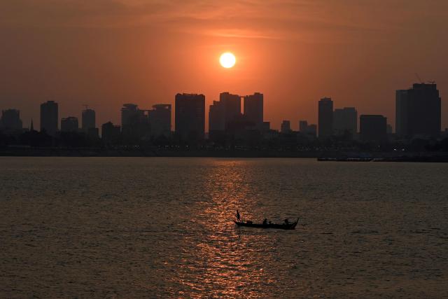 A fisherman rows his boat as the sun sets over the Mekong river in Phnom Penh on March 28, 2026. (Photo by TANG CHHIN Sothy / AFP)
