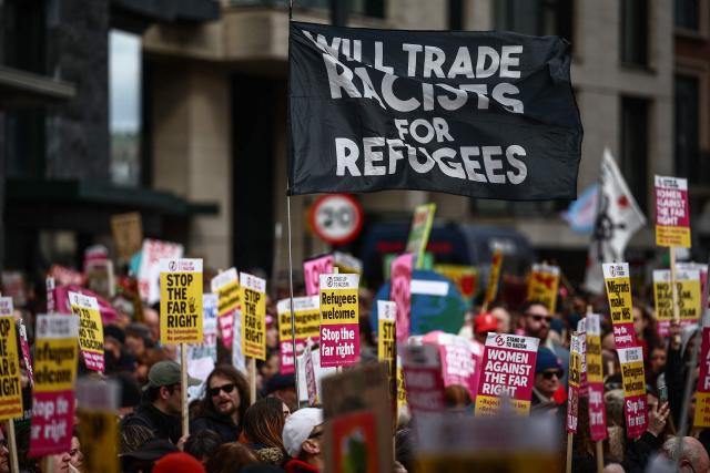 Protesters holding placards and waving flags,including one which reads "Will trade racists for refugees", take part in a march against the far right, organised by the Together Alliance, in central London on March 28, 2026. (Photo by Henry Nicholls / AFP)