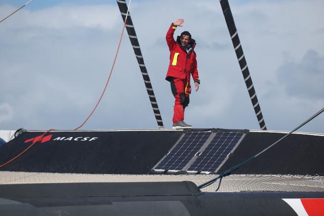 French skipper Guirec Soudée celebrates aboard the maxi-trimaran MACSF shattering the record for sailing around the world from east to west, near Brest on March 28, 2026, completing the voyage in 94 days, 21 hours, and 58 minutes. (Photo by FRED TANNEAU / AFP)