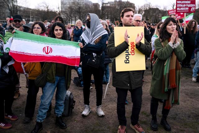Protestors, one carrying an Iranian national flag, shout slogans as they take part in a demonstration against military attacks by the United States and Israel on Iran entitled 'Stop the war against Iran!'  on the Malieveld in The Hague on March 28, 2026. (Photo by Lina Selg / ANP / AFP) / Netherlands OUT