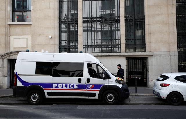 A policeman stands alongside police and private security vehicles outside The Bank of America building in the 8th arrondissement of Paris on March 28, 2026, following an apparent bomb attack attempt. French police stopped an apparent bomb attack outside a US bank in Paris early March 28, 2026, when they arrested a man about to set off a homemade explosive device, sources close to the case told AFP. The incident occurred around 3:30 am (0130 GMT) in front of a Bank of America building in the chic 8th arrondissement, a couple of streets from the Champs-Elysees. (Photo by Sebastien DUPUY / AFP)