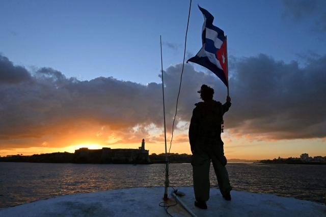 (FILES) An activist waves a Cuban flag on board the vessel Maguro -- symbolically renamed "Granma 2.0" as a tribute to the yacht used by Fidel Castro's guerrilla fighters to launch their revolution in 1956 -- as it arrives from Mexico with humanitarian aid as part of the Nuestra America convoy, docking at the port of Havana on March 24, 2026. Two sailboats that disappeared while taking humanitarian aid from Mexico to Cuba have been located by the Mexican Navy and its crew is safe, organizers and Mexican authorities said on March 28, 2026. (Photo by YURI CORTEZ / AFP)