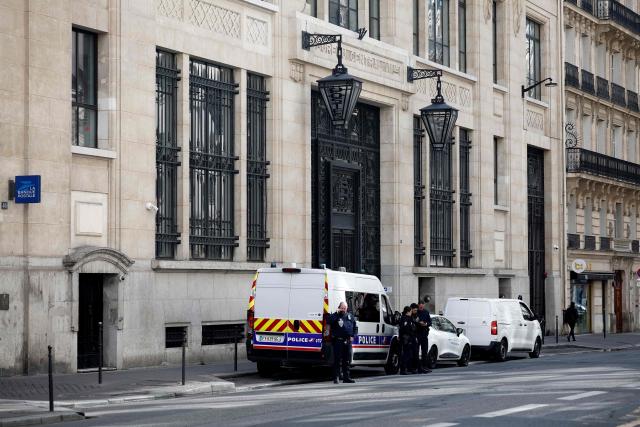 Police officials stand alongside police and private security vehicles outside The Bank of America building in the 8th arrondissement of Paris on March 28, 2026, following an apparent bomb attack attempt. French police stopped an apparent bomb attack outside a US bank in Paris early March 28, 2026, when they arrested a man about to set off a homemade explosive device, sources close to the case told AFP. The incident occurred around 3:30 am (0130 GMT) in front of a Bank of America building in the chic 8th arrondissement, a couple of streets from the Champs-Elysees. (Photo by Sebastien DUPUY / AFP)