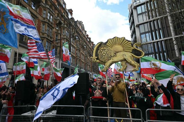 Counter-protesters wave US, Israeli and pre-revolution Iranian flags as a pro-palestinian march organised by the Palestine Coalition passes by, in central London on March 28, 2026.  (Photo by JUSTIN TALLIS / AFP)