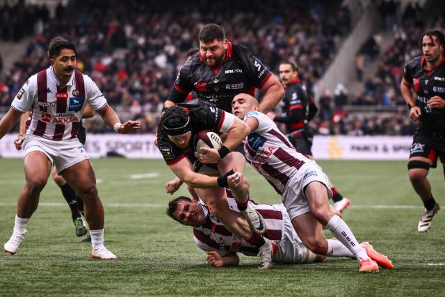 Lyon's British flanker Sam Simmonds (C) is tackled by Bordeaux-Begles' French scrum-half Maxime Lucu (2R) during the French Top14 rugby union match between Lyon Olympique Universitaire Rugby and Union Bordeaux-Begles (UBB) at the Gerland Stadium in Lyon, central-eastern France on March 28, 2026. (Photo by ARNAUD FINISTRE / AFP)