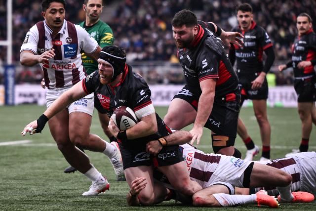 Lyon's British flanker Sam Simmonds (CL) is tackled by Bordeaux-Begles' French scrum-half Maxime Lucu (CR) during the French Top14 rugby union match between Lyon Olympique Universitaire Rugby and Union Bordeaux-Begles (UBB) at the Gerland Stadium in Lyon, central-eastern France on March 28, 2026. (Photo by ARNAUD FINISTRE / AFP)